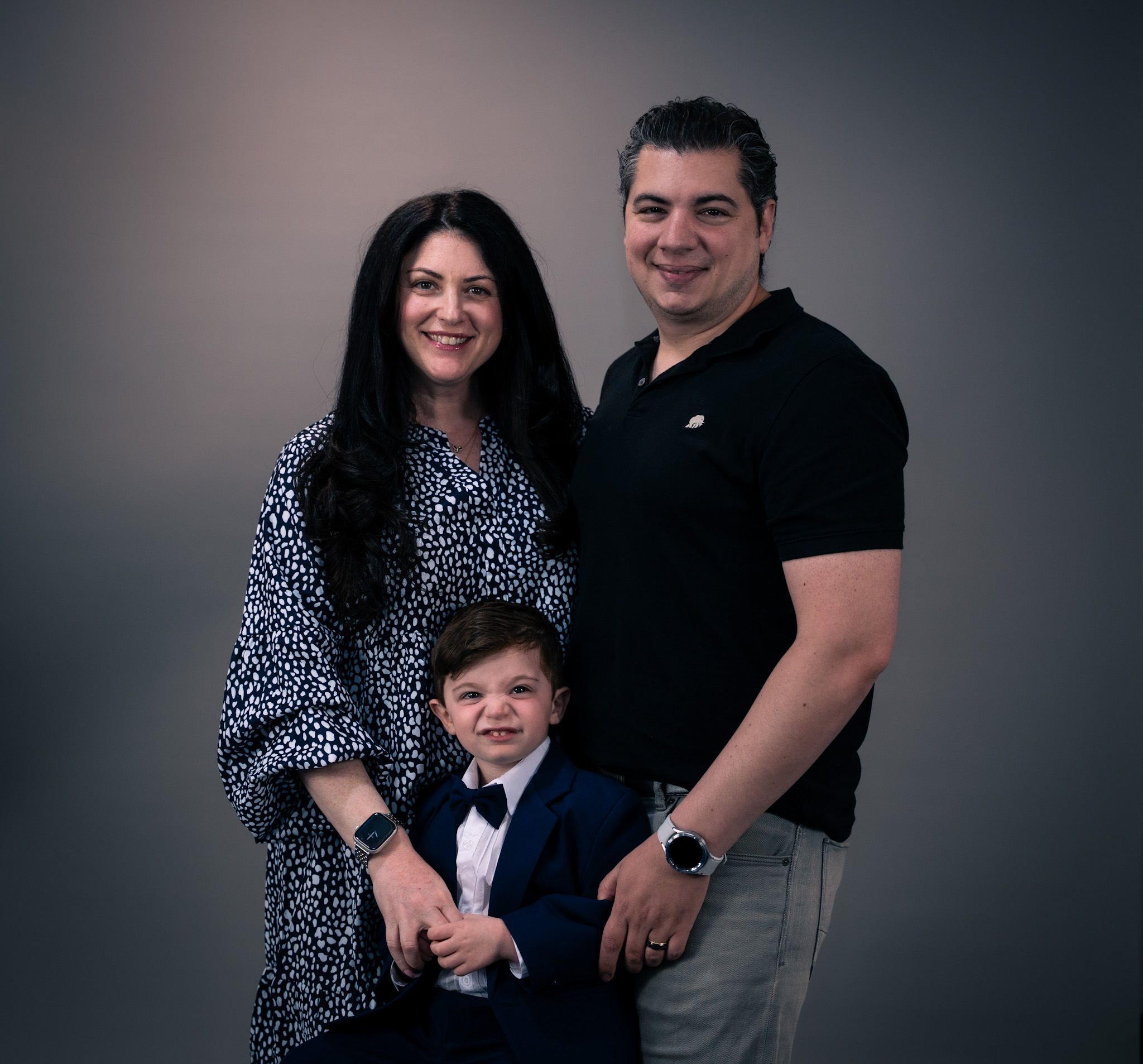Professional family studio portrait with parents and child in formal attire