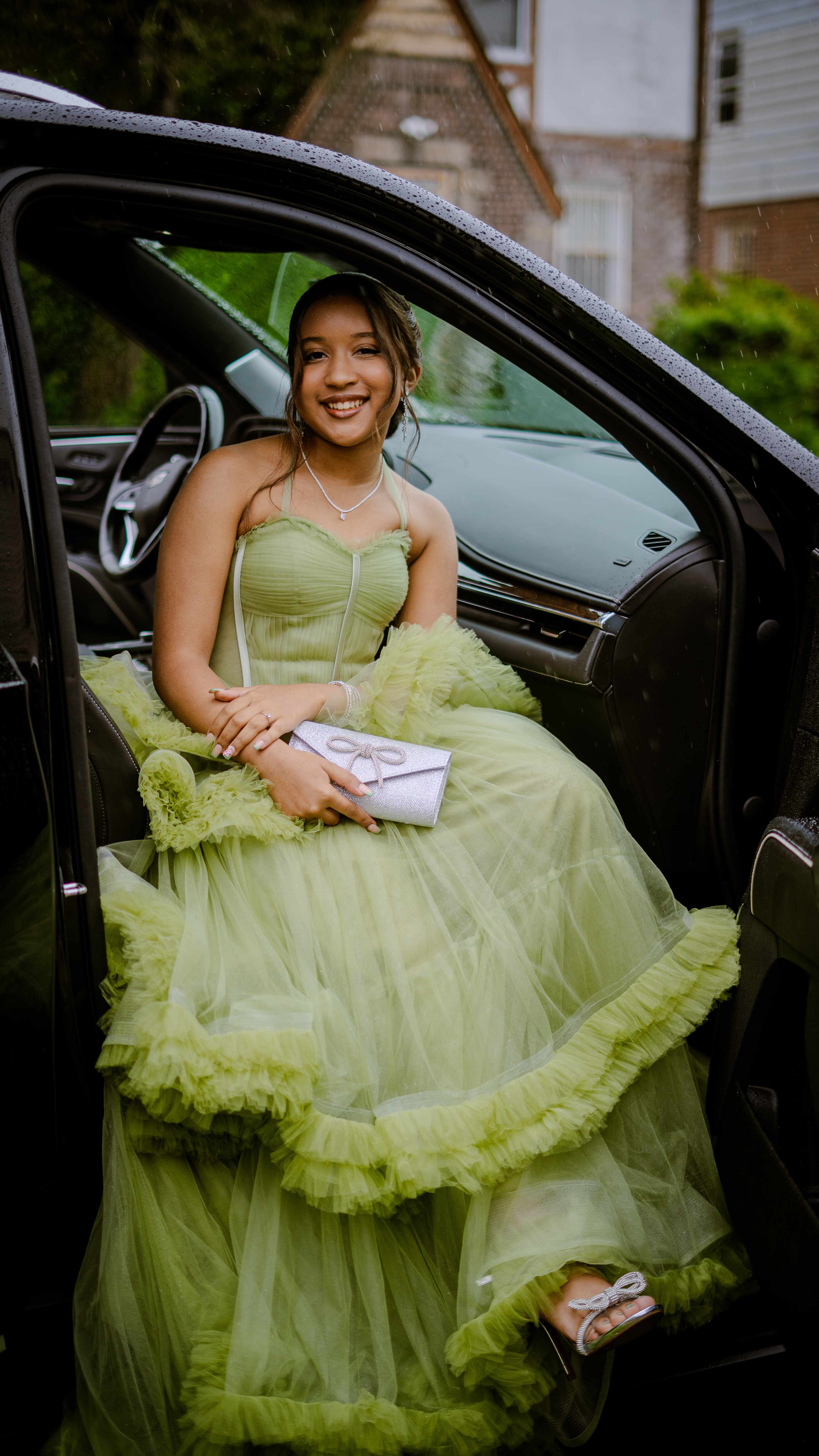 Graduate sitting in car with formal dress and purse