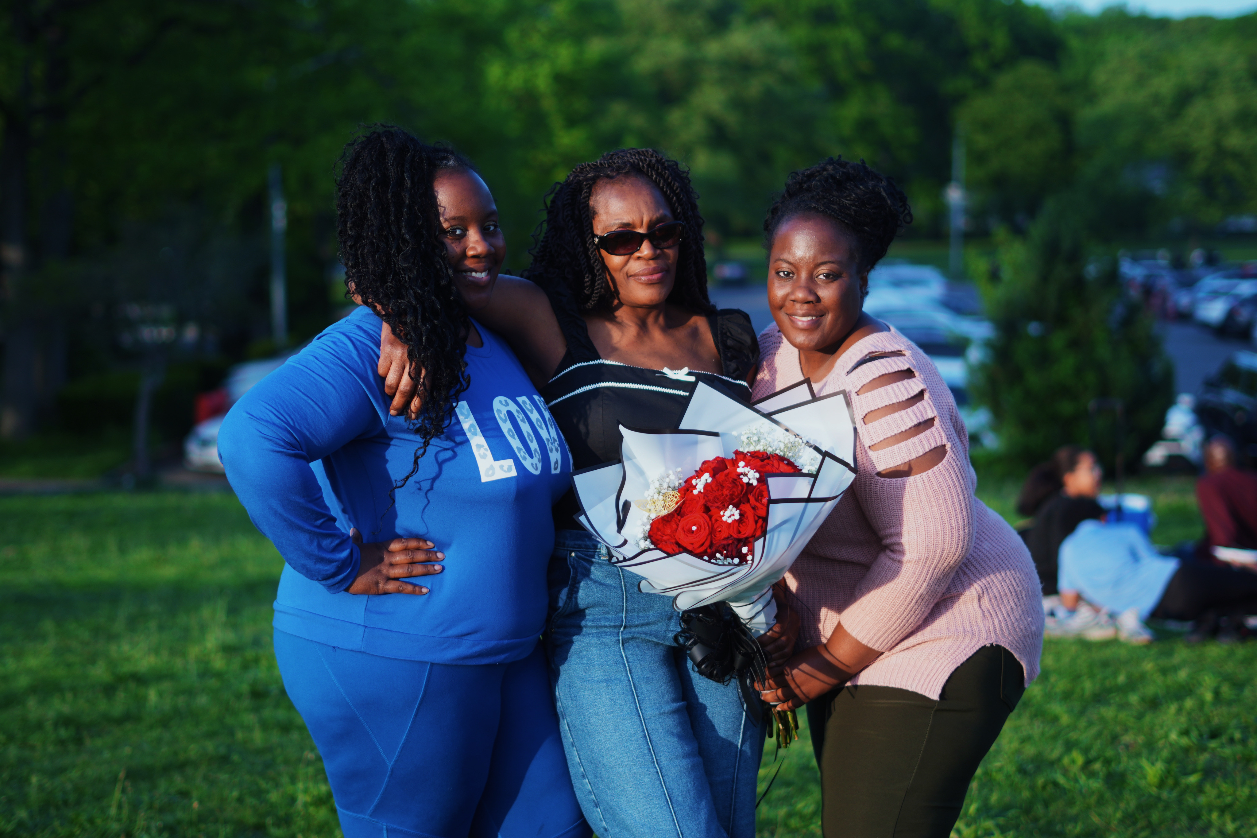 Graduate with family members holding red roses bouquet