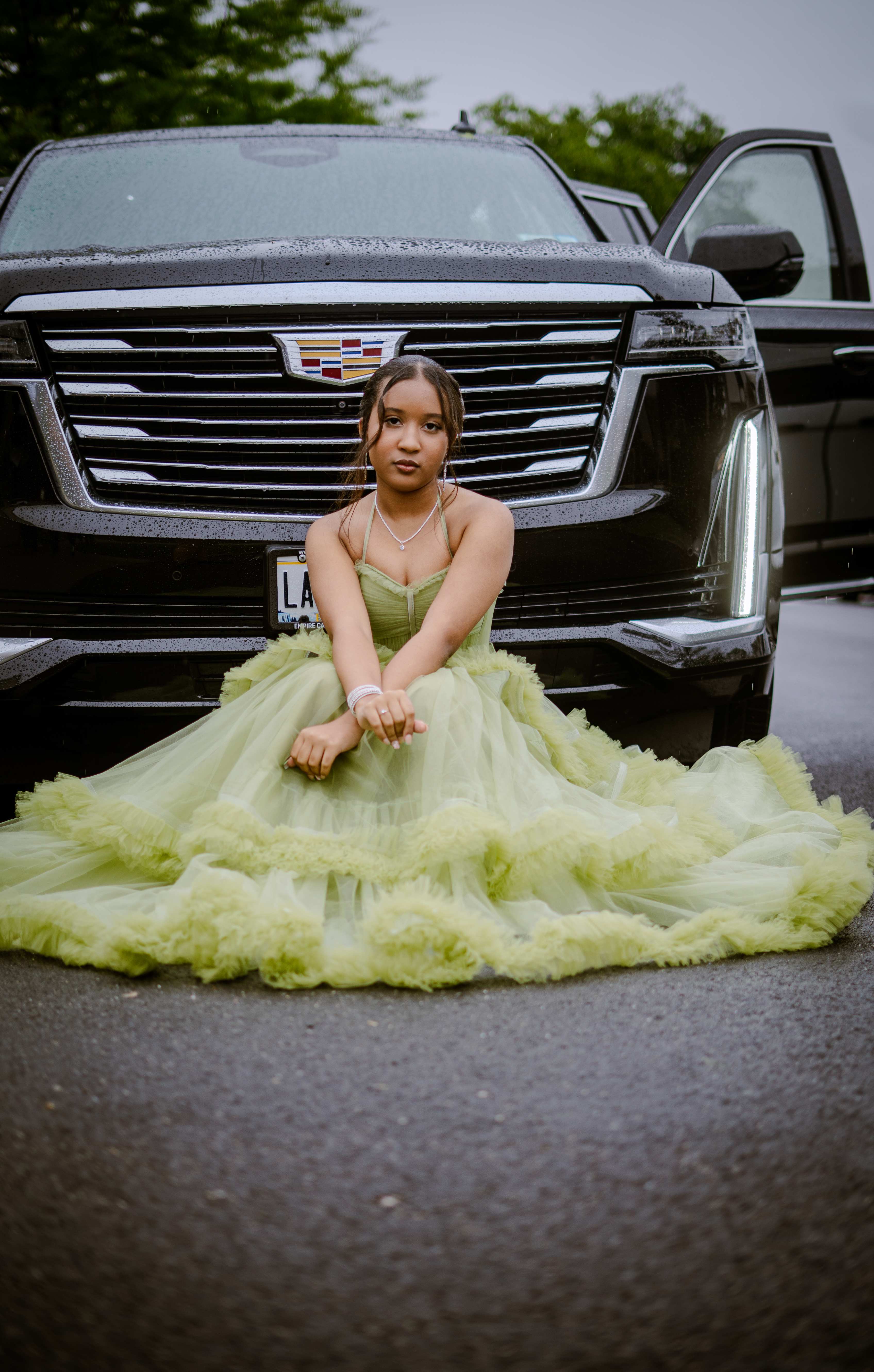 Graduate in mint green dress in front of luxury car
