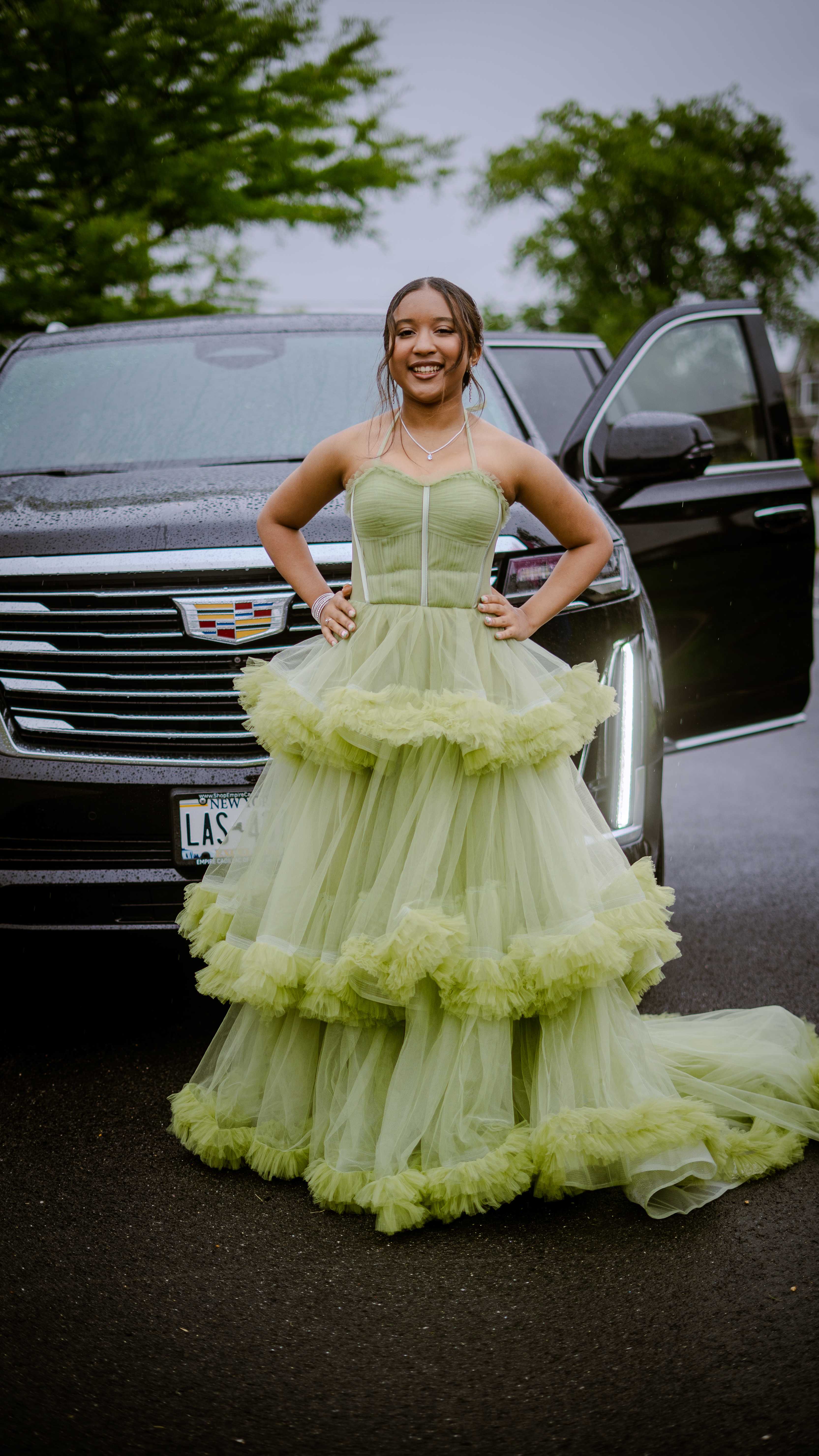Graduate in mint green dress standing by car